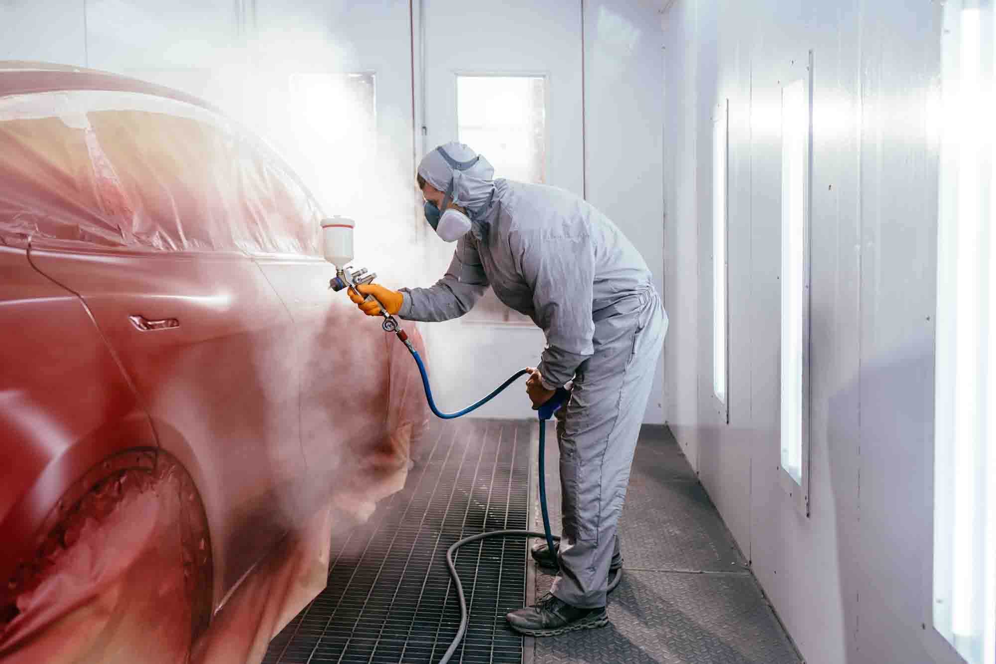 Painter in booth spraying red suv wearing protective gear - auto paint repair - california reflections auto body & paint